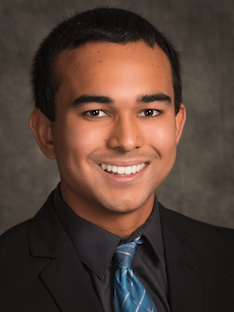 A man smiling and wearing a suit and tie