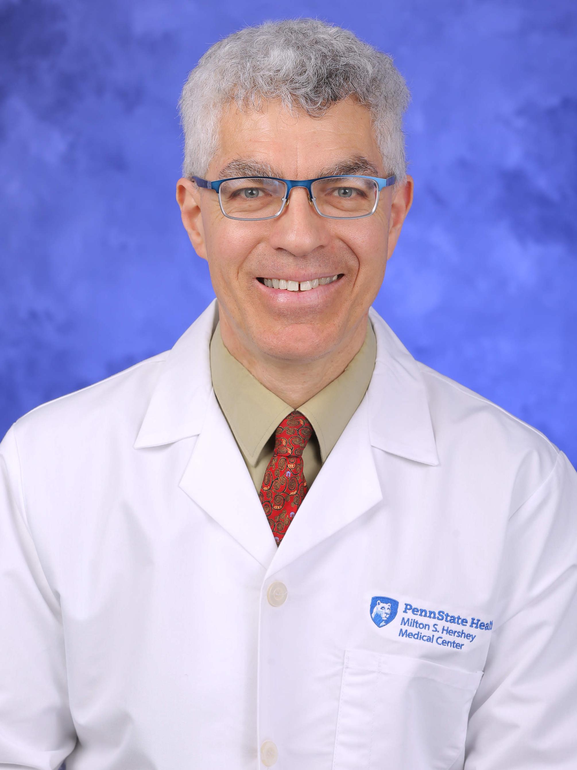 Dr. David Rabago poses for a professional headshot, wearing a physician's coat.