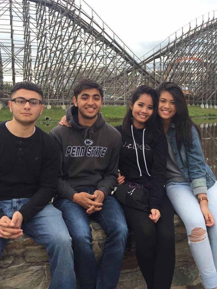 A group of students sit in front of a roller coaster