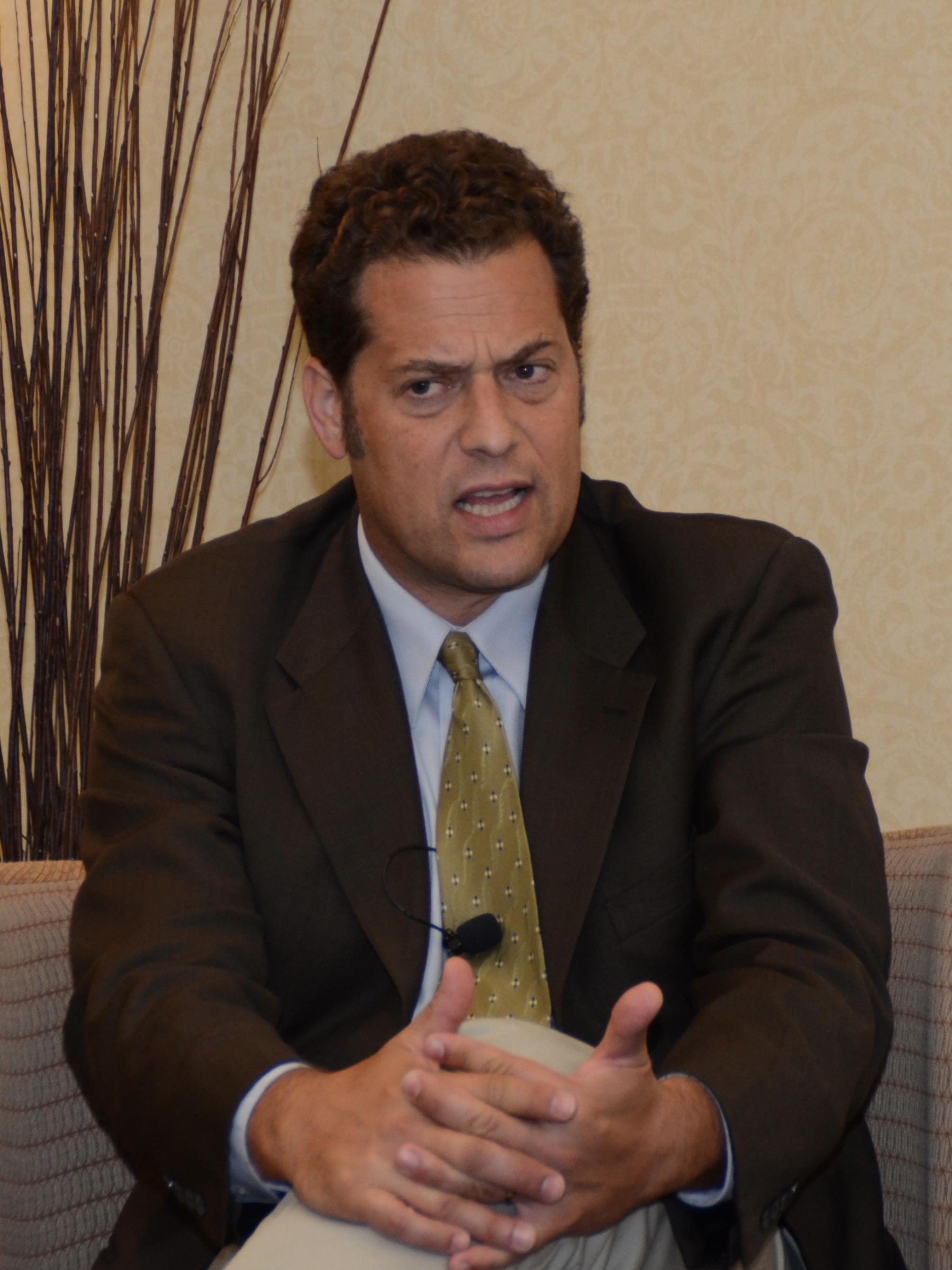 man sitting in chair speaking to audience