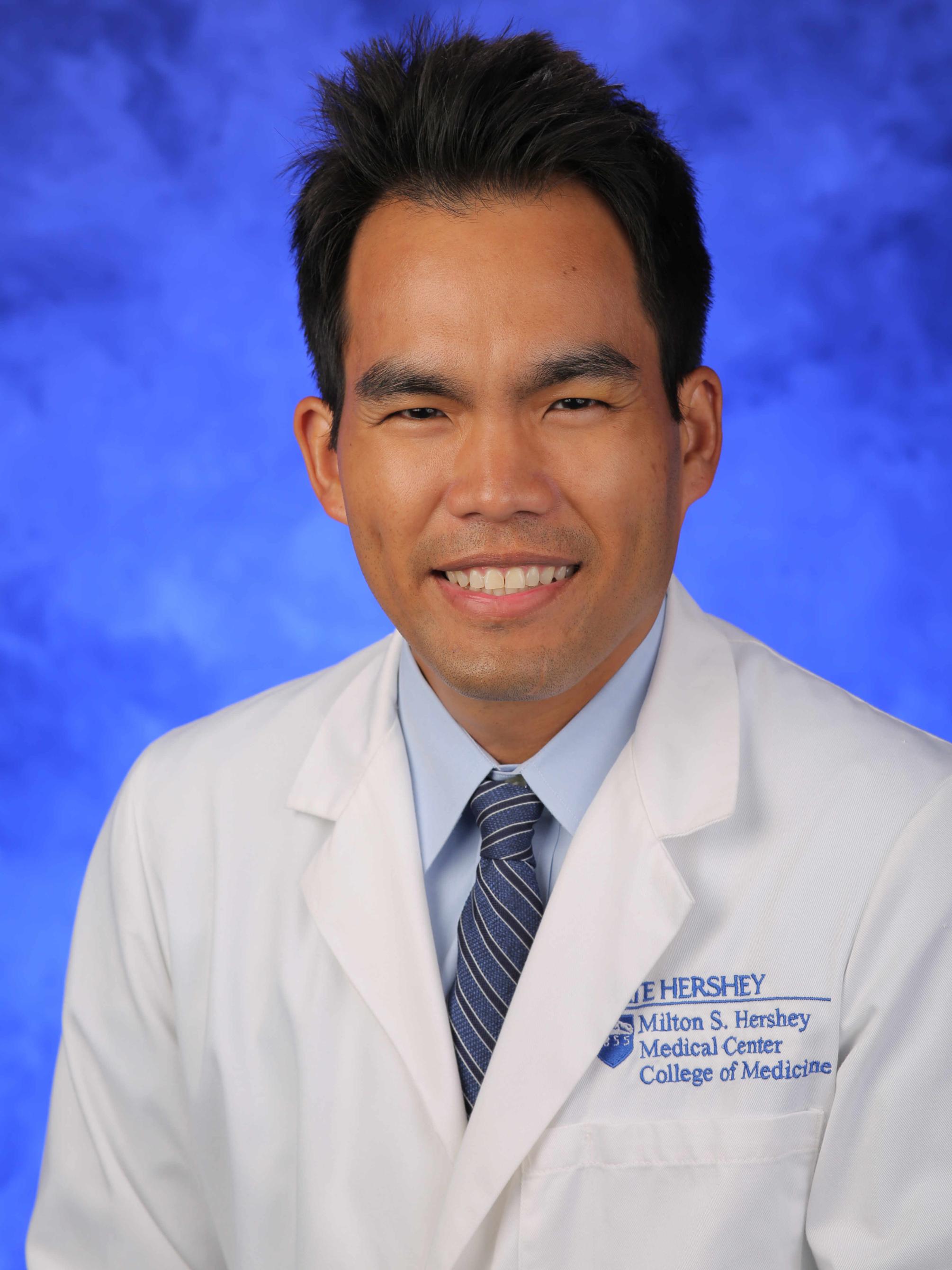 A professional headshot of Dr. Natthapol Songdej, who wears a tie and physician's coat