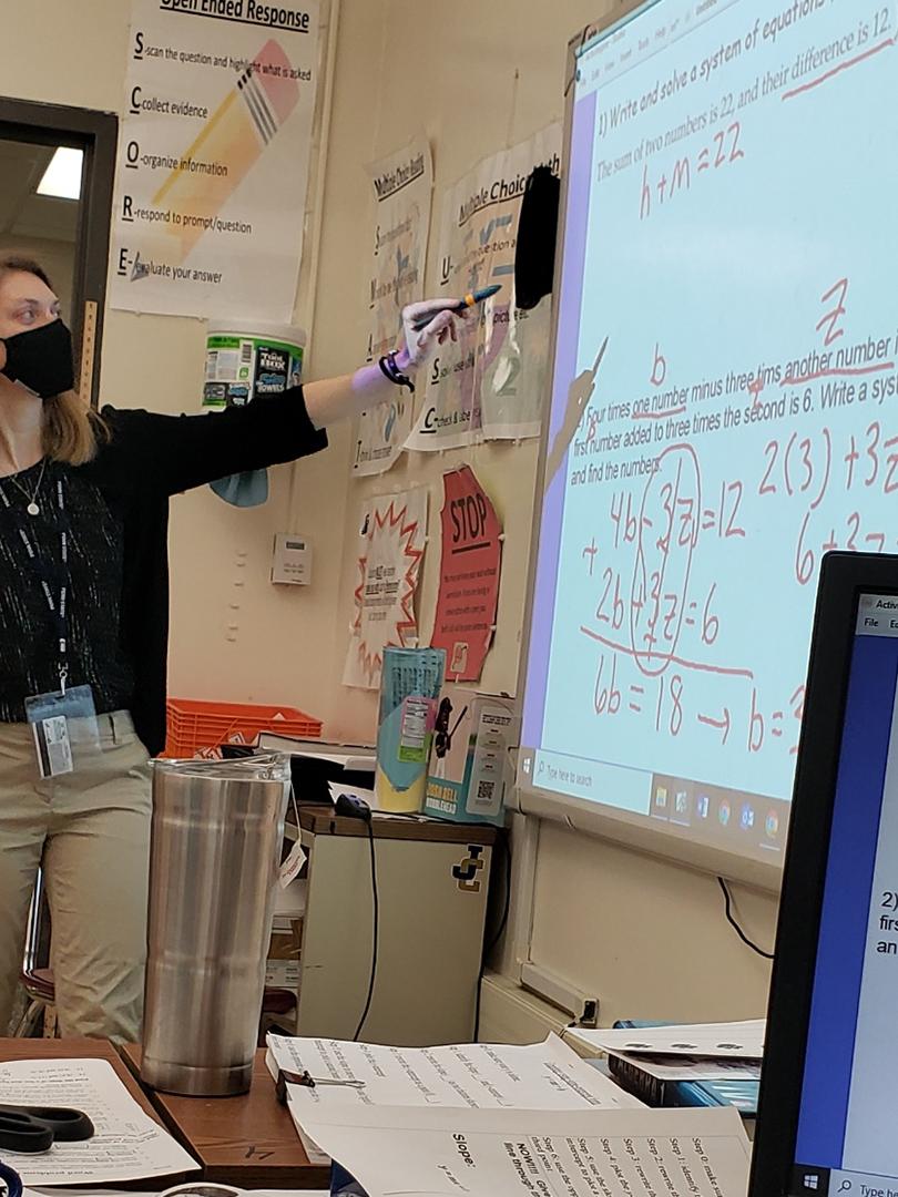 Student Teacher pointing to math assignment on projector screen.