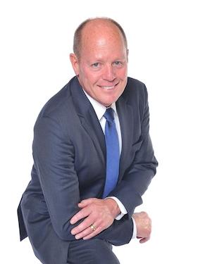 person in business suit leaning on knee and smiling for professional headshot photo