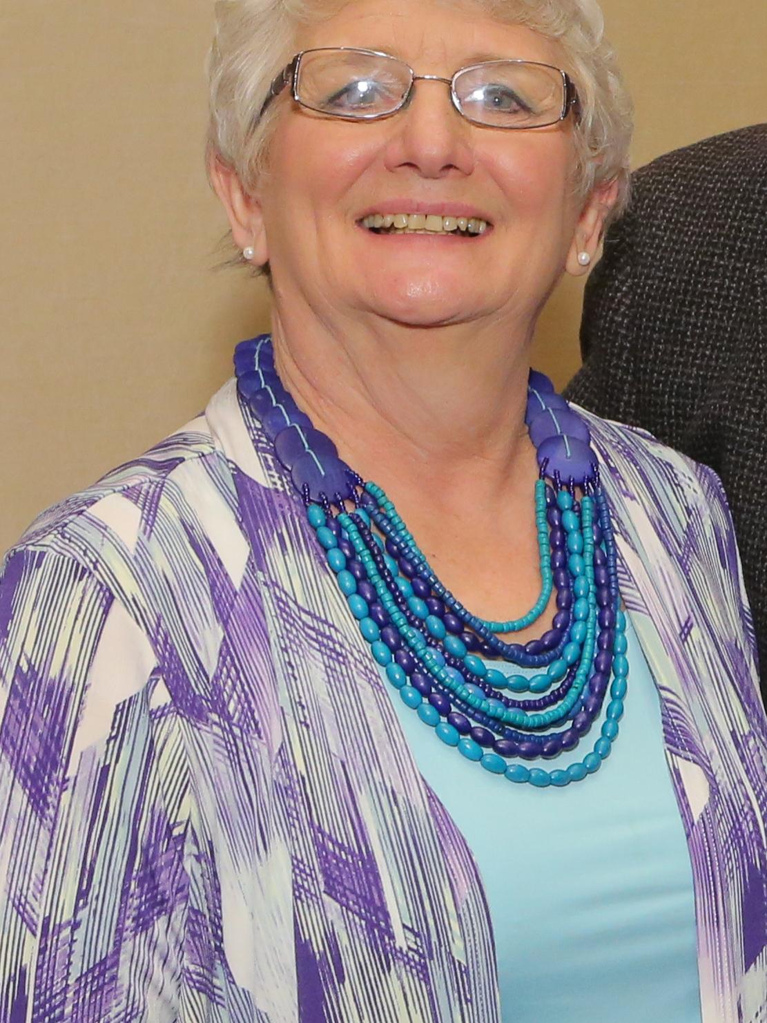 Sue Espenshade poses for a photo against a beige backdrop.