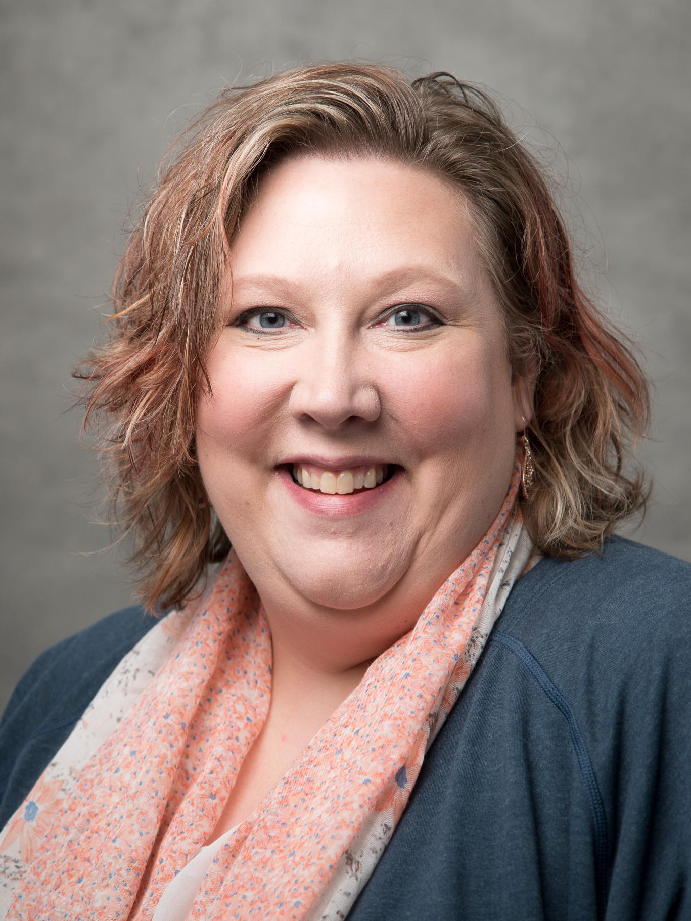 photo portrait of woman wearing blue-gray sweater and coordinating peach floral scarf