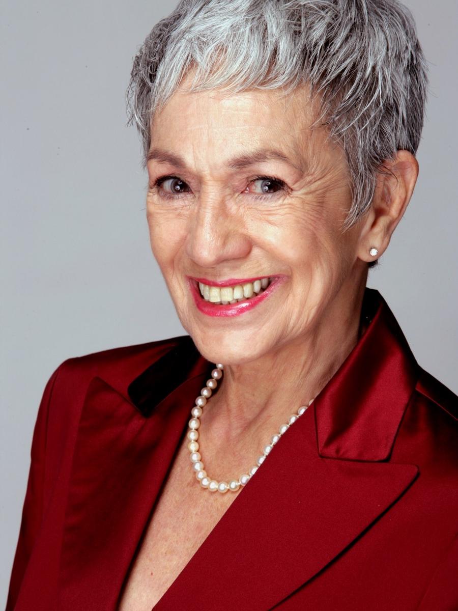 A woman shown from the shoulders up smiles at the camera