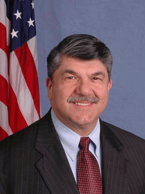 Richard L. Trumka poses before a United States flag