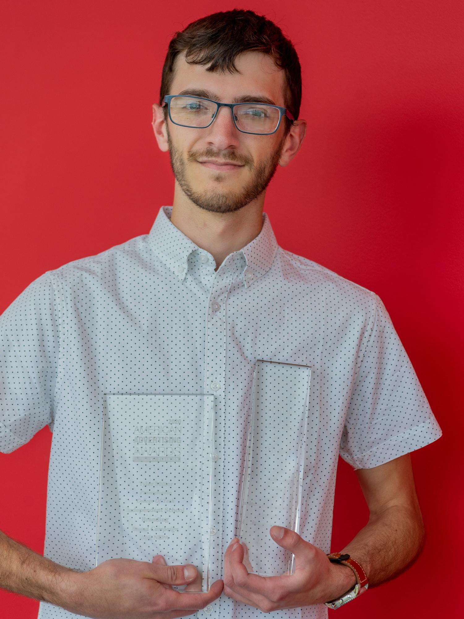 Tyler Miller holding his two glass trophies