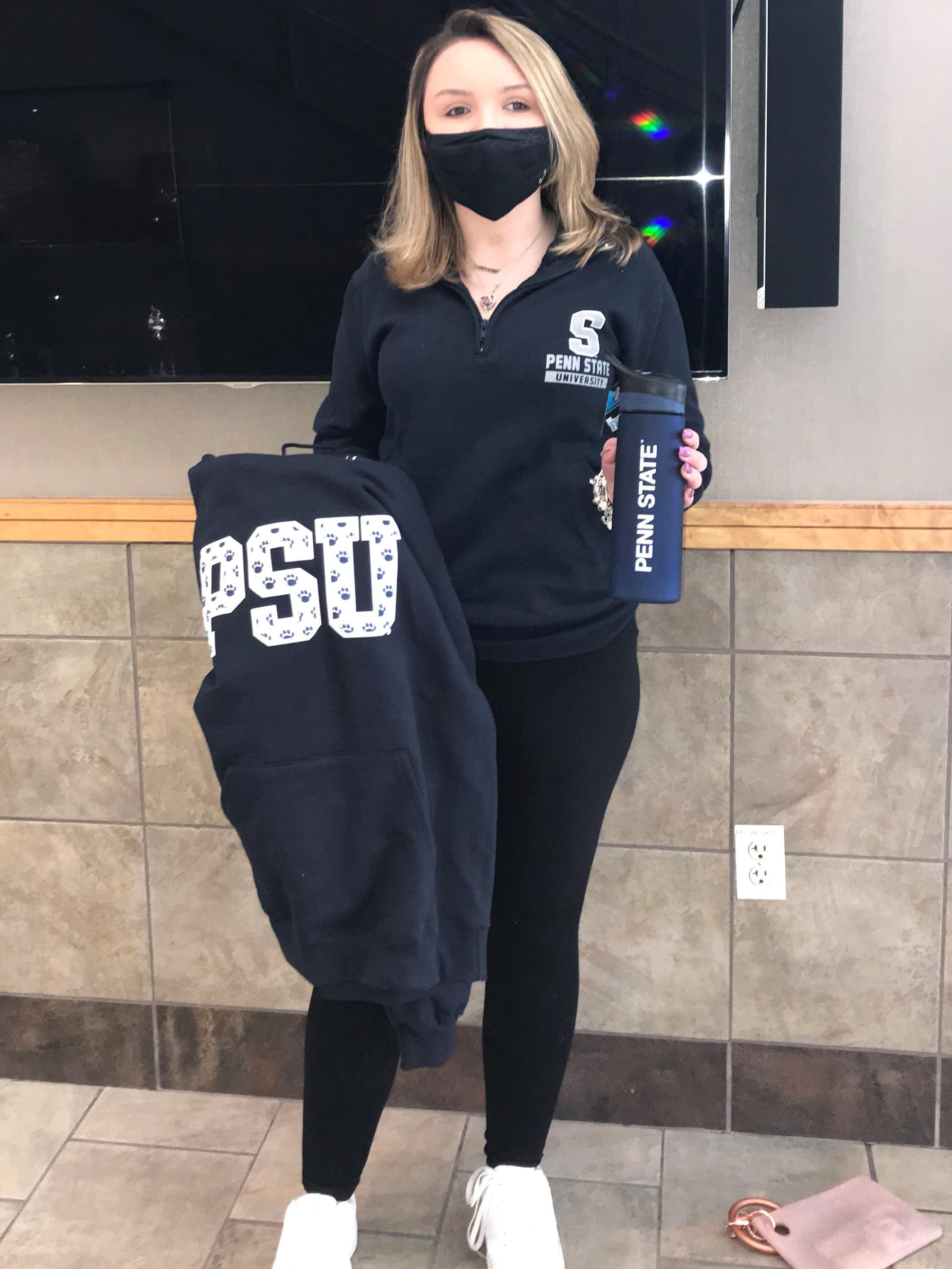 Female student holding a Penn State branded water bottle and sweatshirt.