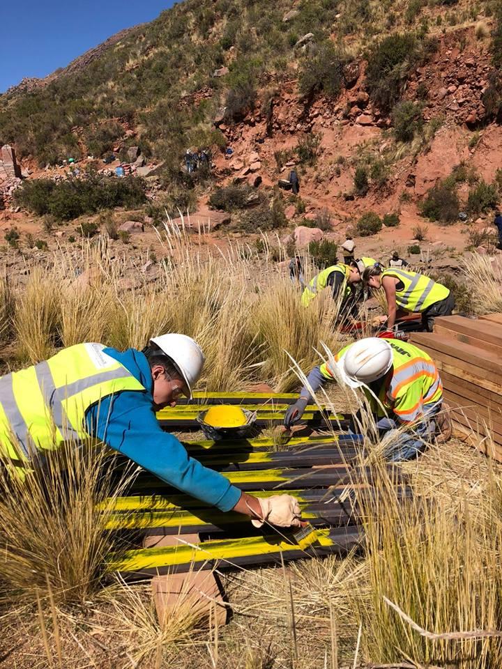 Team members painting metal yellow.