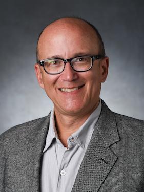 A professor smiles for a professional headshot.