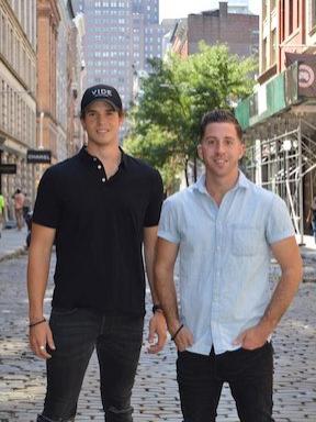 two men standing on a New York City street posing and smiling