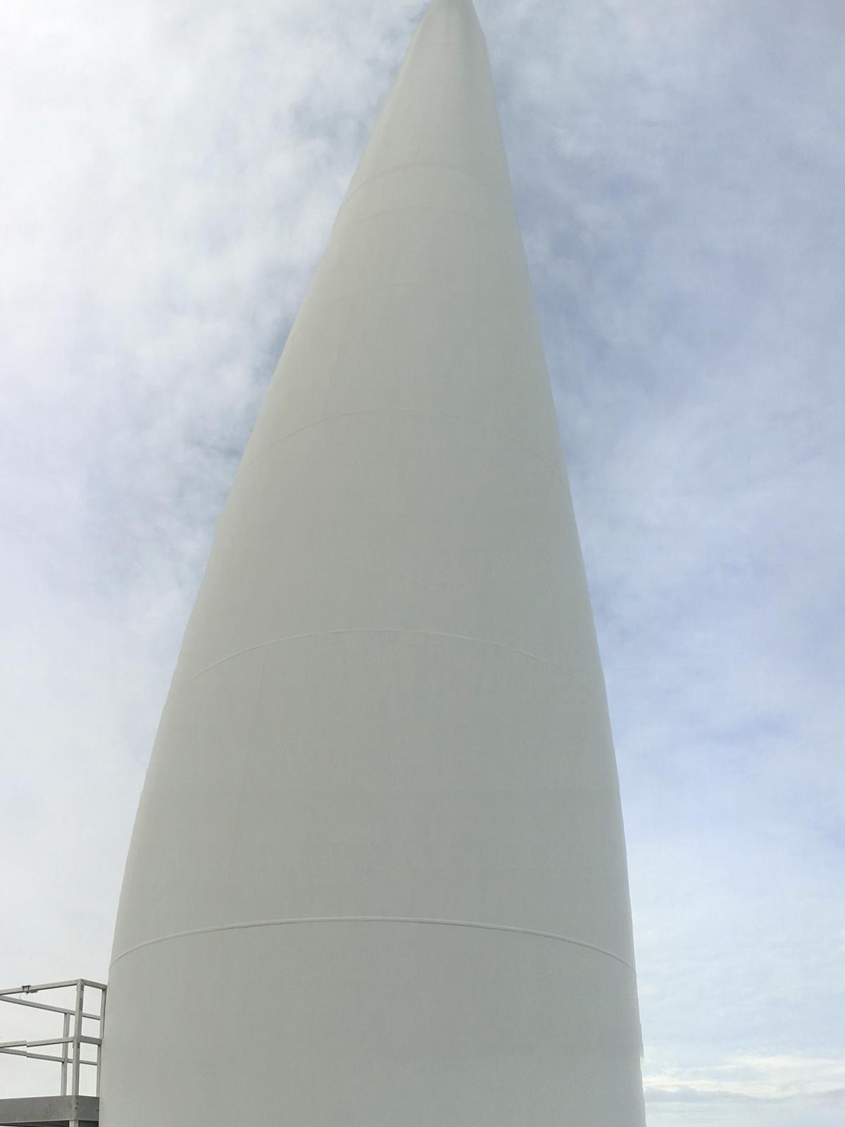 Jenna Hakun, a junior majoring in energy engineering, hugs a wind turbine during a recent trip to New Zealand. Wind power provides about 5 percent of the nation’s 80 percent renewable energy.