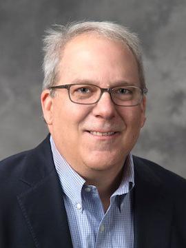 Man smiles for the camera in suit jacket.