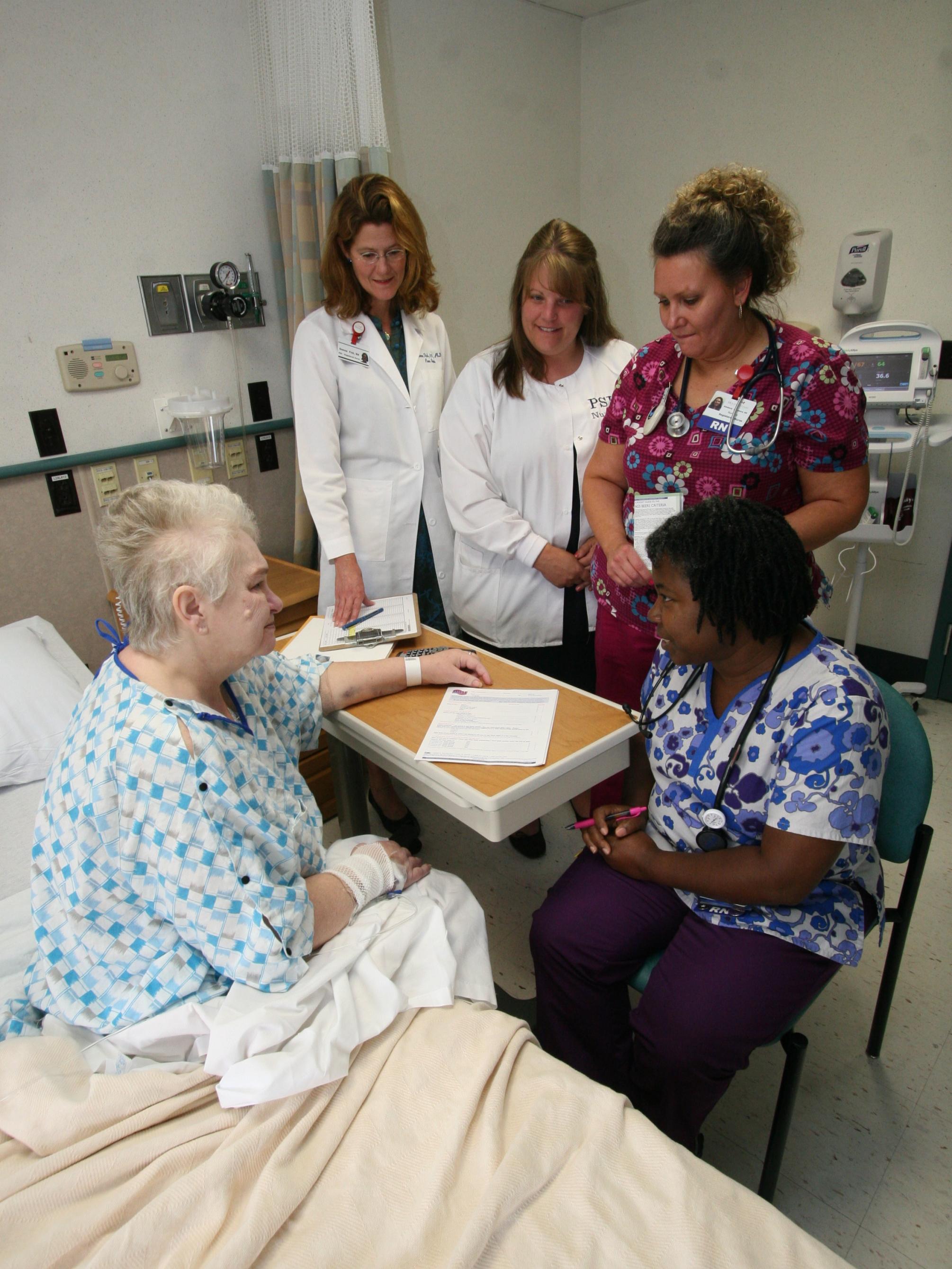 patient in hospital bed with nursing staff gathered around