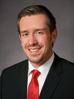 professor in suit and red necktie smiling and posing for a professional headshot