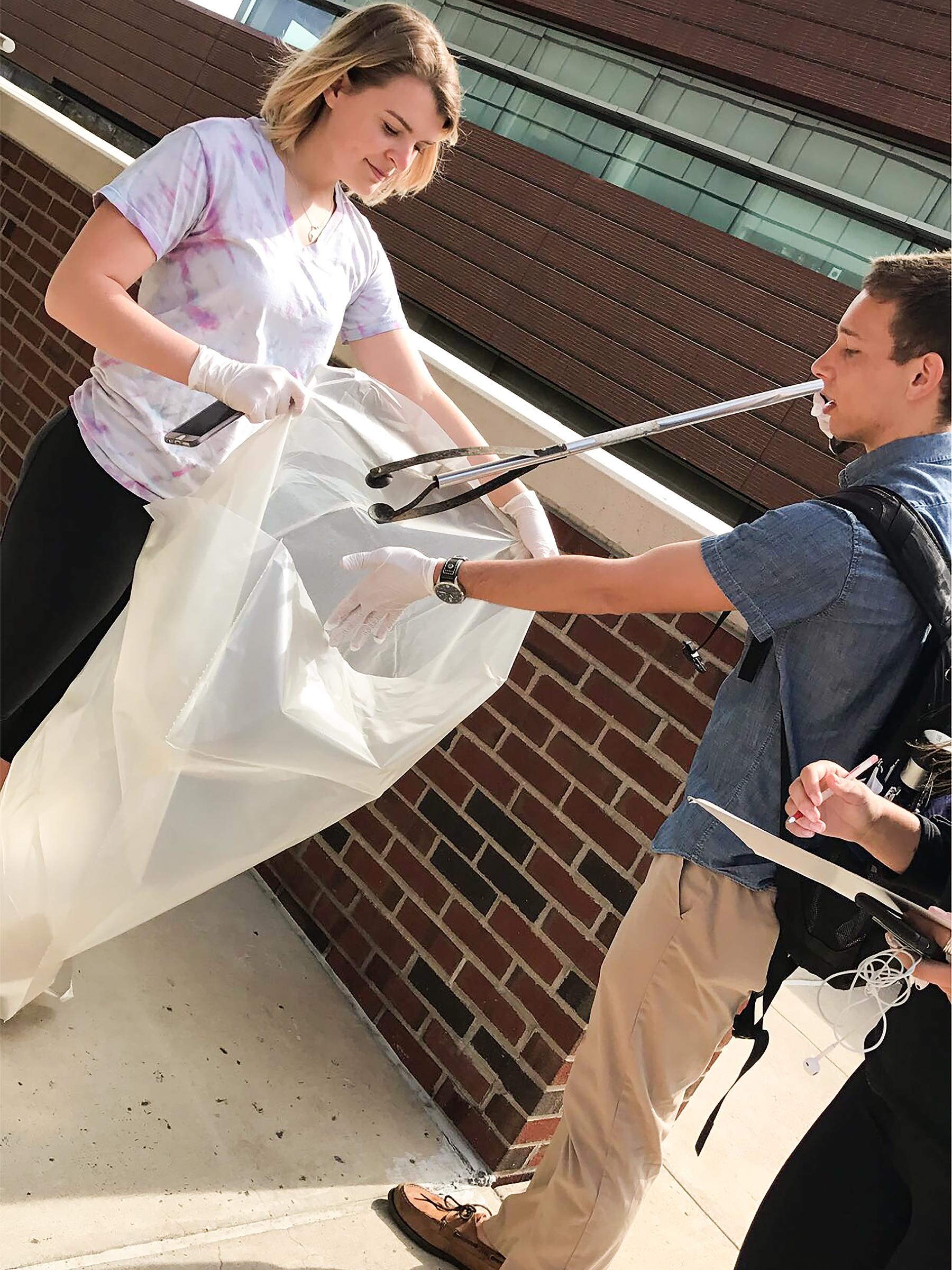 Two students pick up cigarette butts