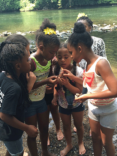 Children examine a snail by the Schuylkill River