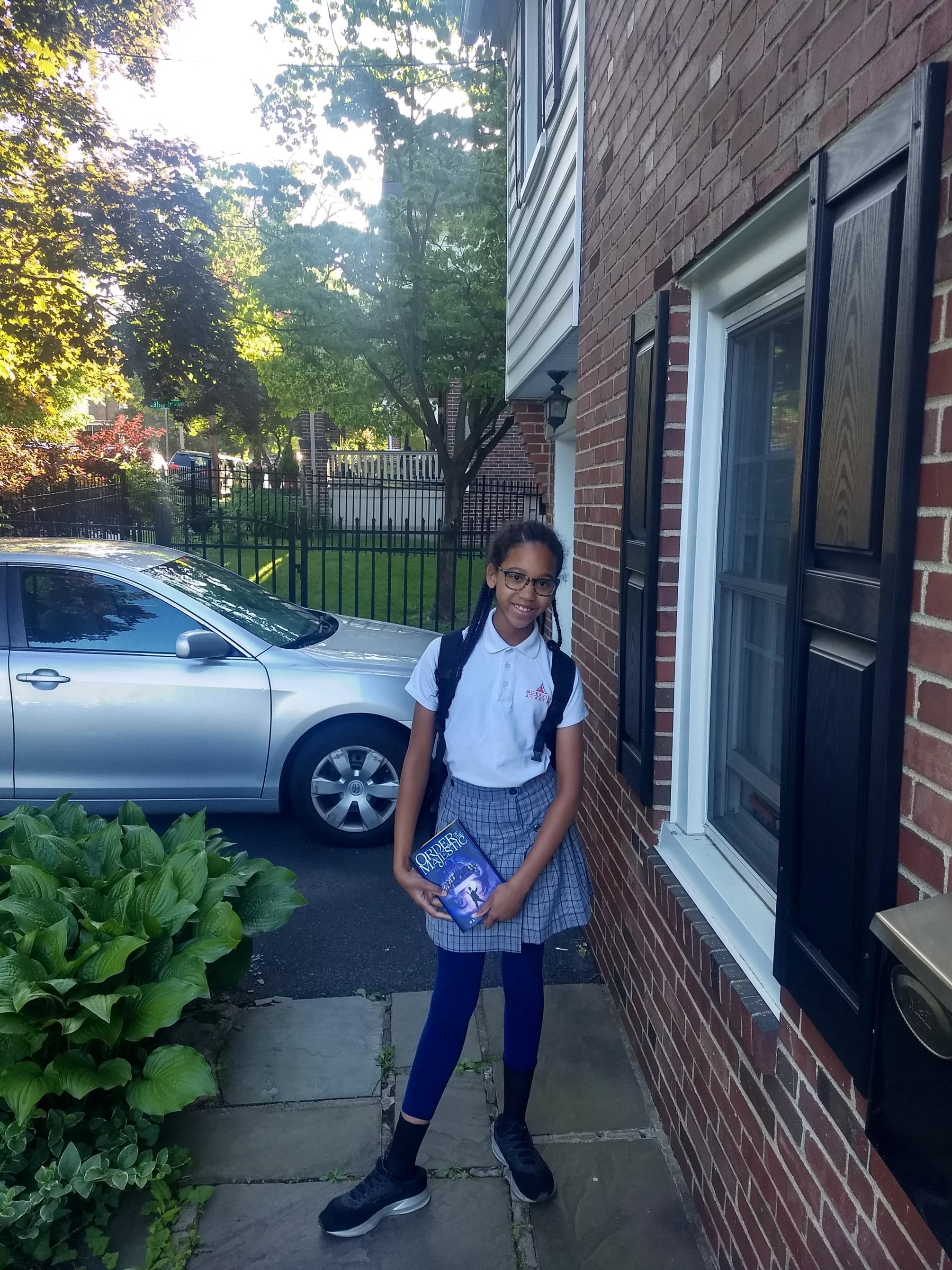 young girl in school uniform holding a book