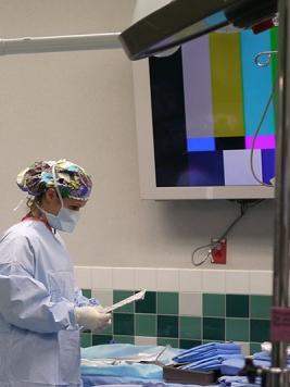 A neurosurgery scrub nurse in a sterile gown and gloves prepares an operating room for surgery 