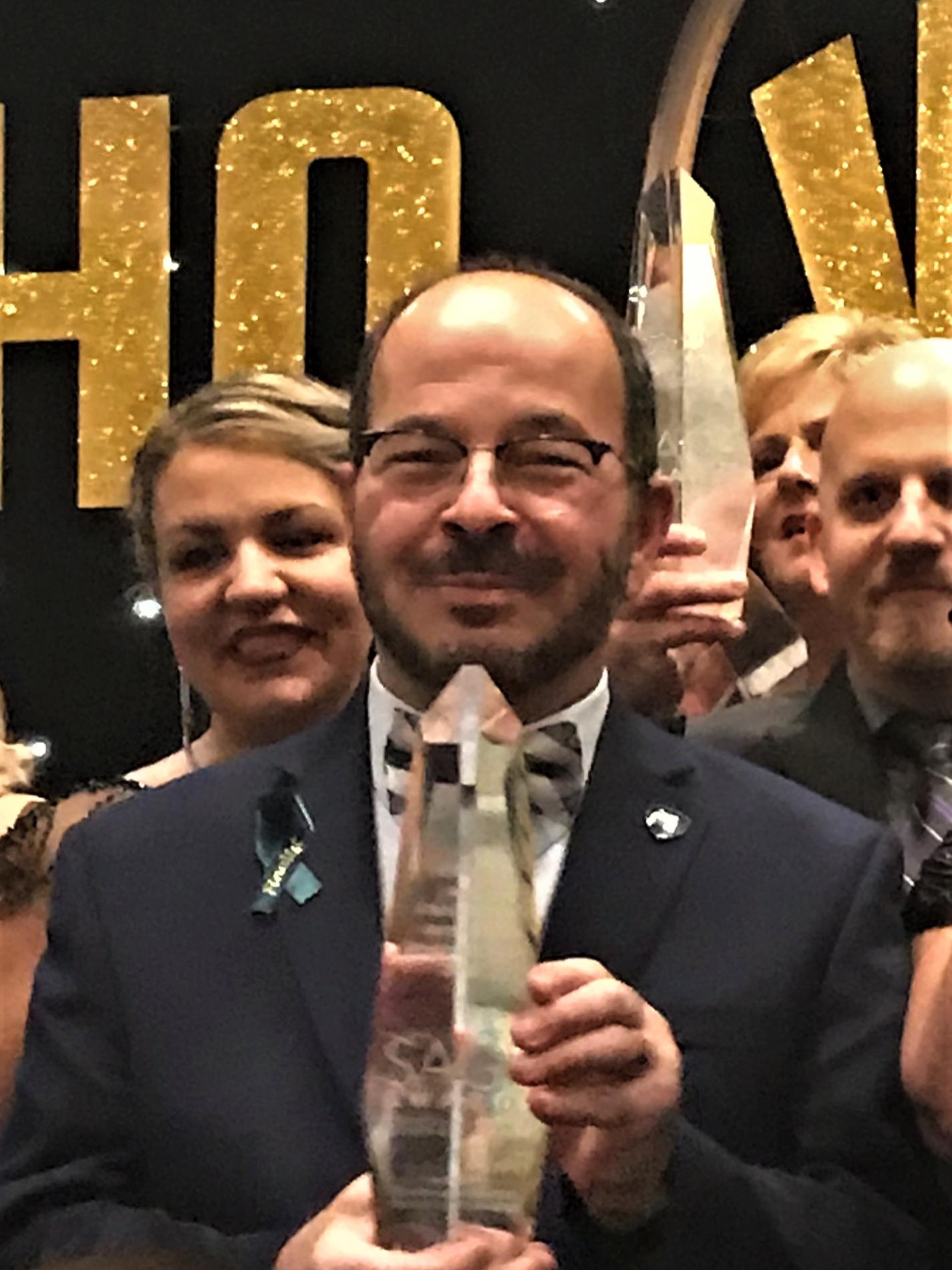 Chancellor Wafa holding Sage Award at ceremony