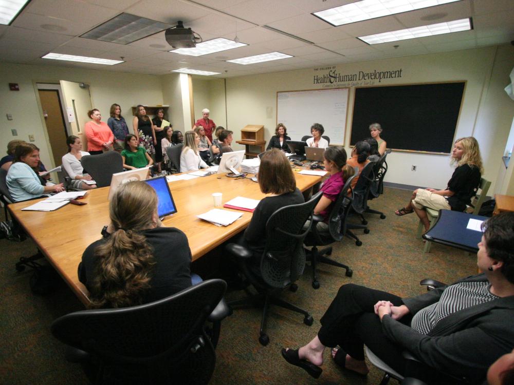 A group of nursing students sit at a table during a discussion.