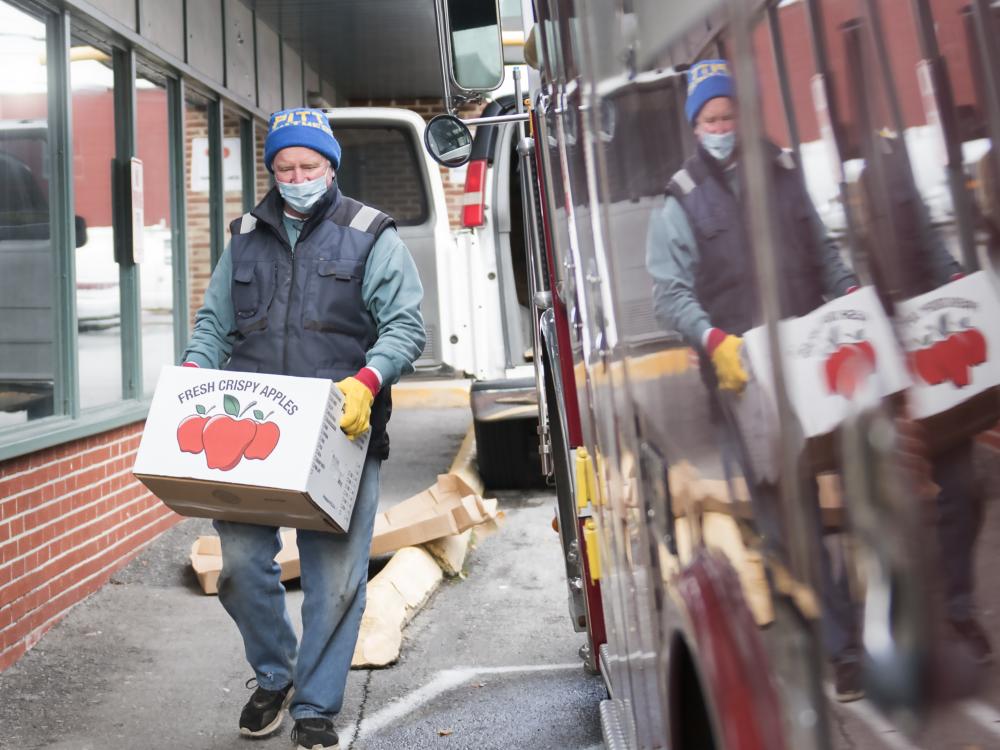 Jim Yonushonis, a volunteer with the YMCA of Centre County, carries a box of fresh apples to distribute for free to local families outside the YMCA in Bellefonte.