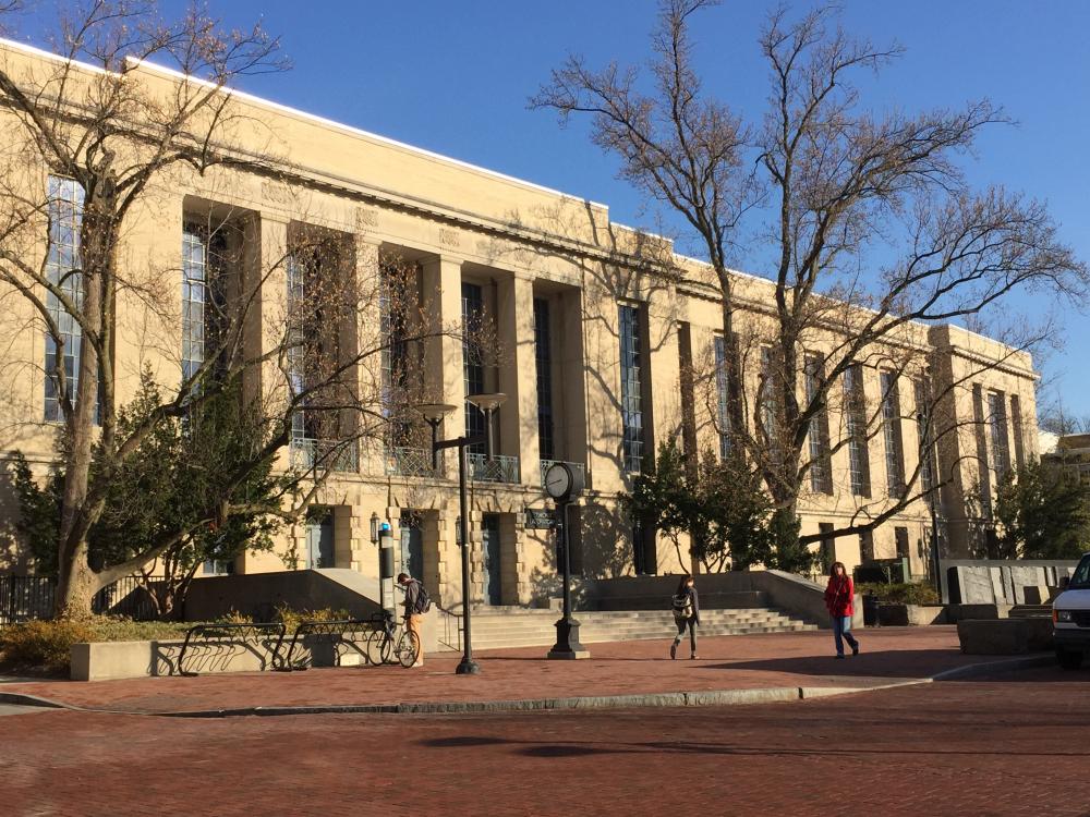 Golden morning sun passes through bare trees and lights the facade of Osmond Lab as students pass. 