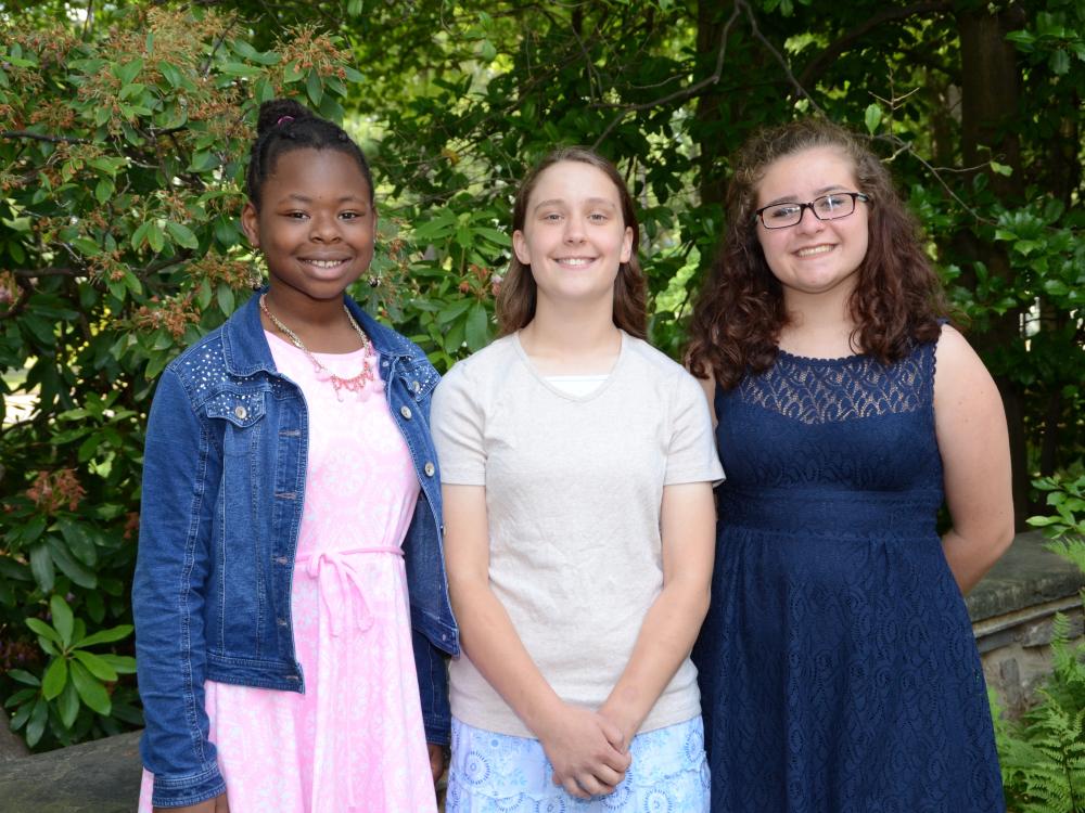 2016 Letters about Literature winners; outdoor photo of three female students standing in front of green foliage