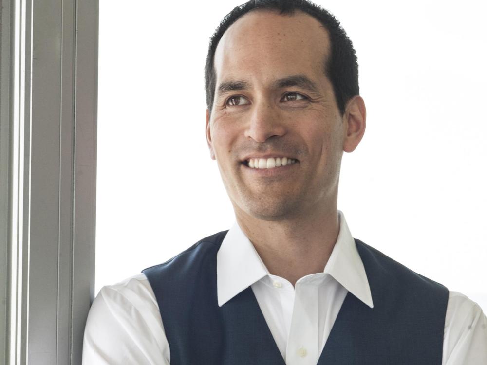 Ian Truitner poses in front of floor-to-ceiling glass windows