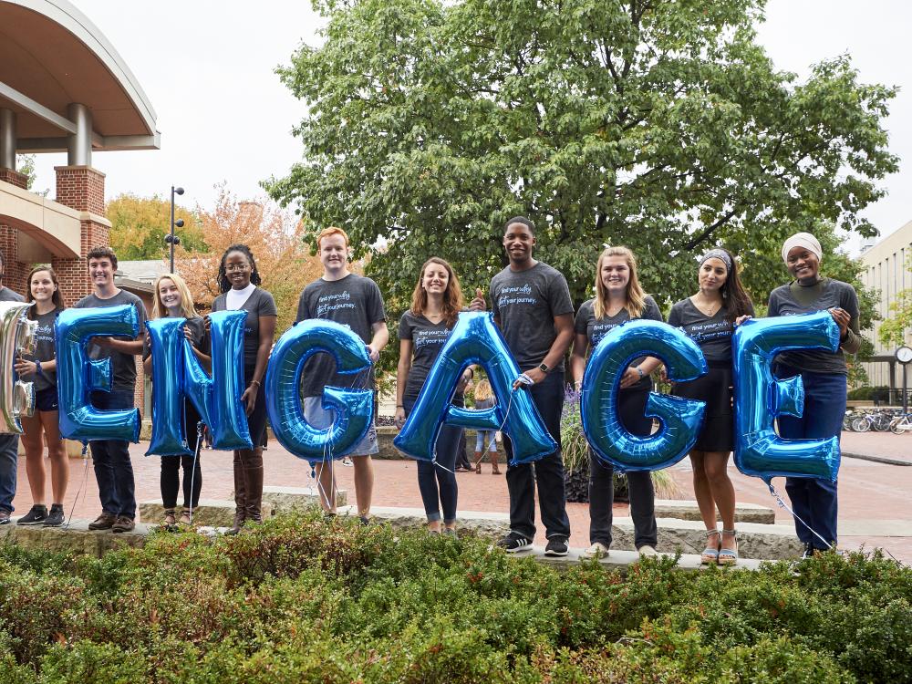 Line of students holding balloons that spell E-N-G-A-G-E