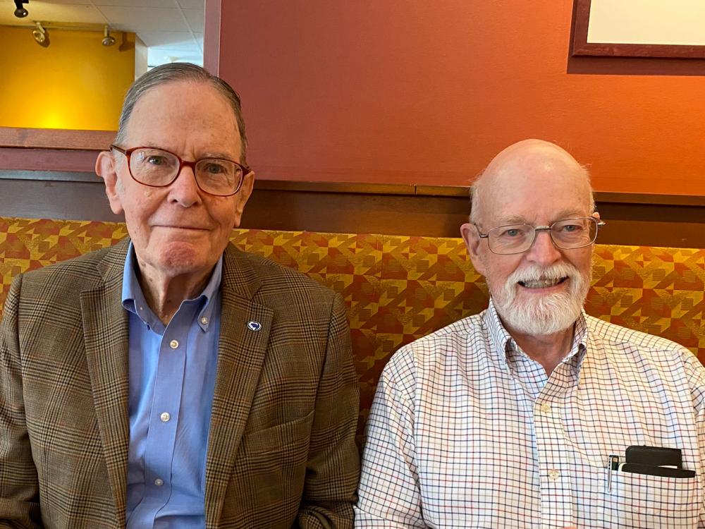 two men sit at restaurant booth