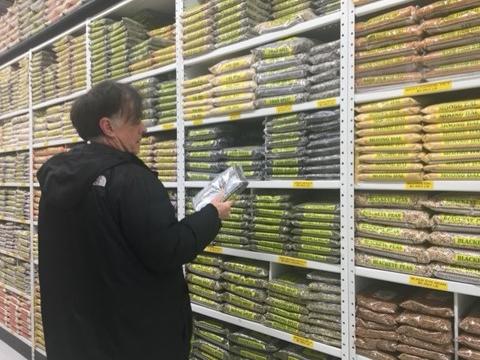 A person standing in front of wall of shelves of packages of beans