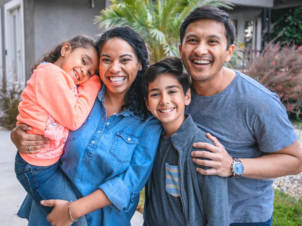 Hispanic mother, father, daughter, and son standing together outside