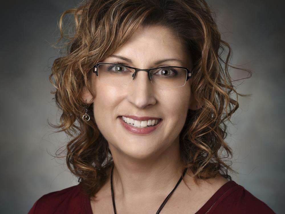 A woman in glasses smiles for her headshot