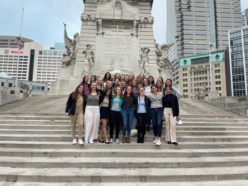 group of students standing on the steps of a monument in Indianapolis, Indiana, smiling and posing for a group photo.