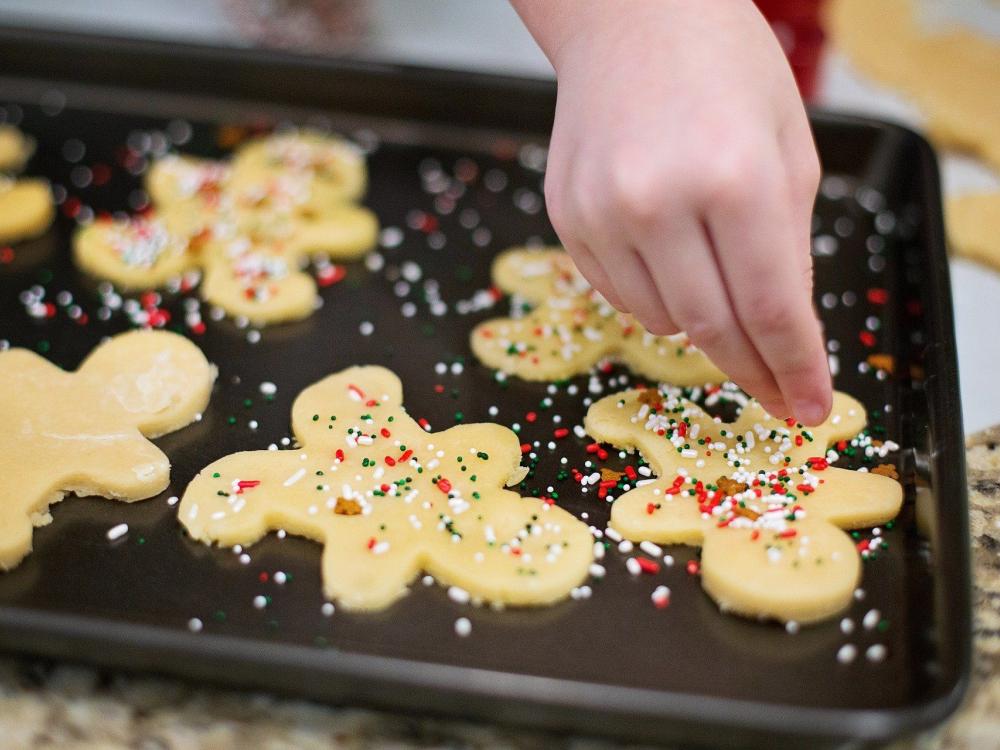 Baker putting sprinkles on Christmas cookies