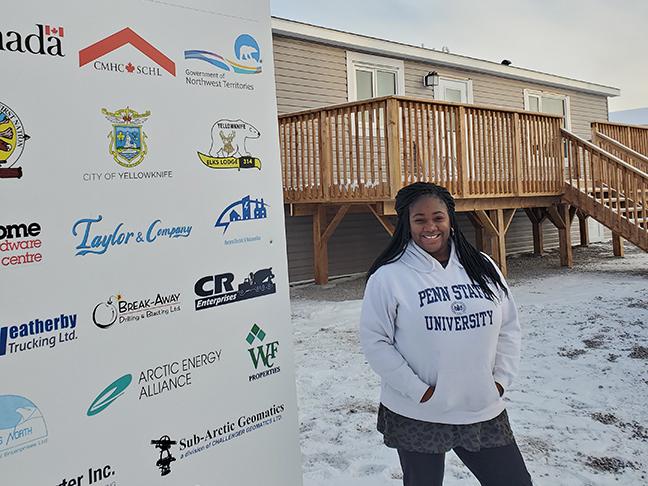 Miriam Pallard standing next to a Habitat for Humanity sign