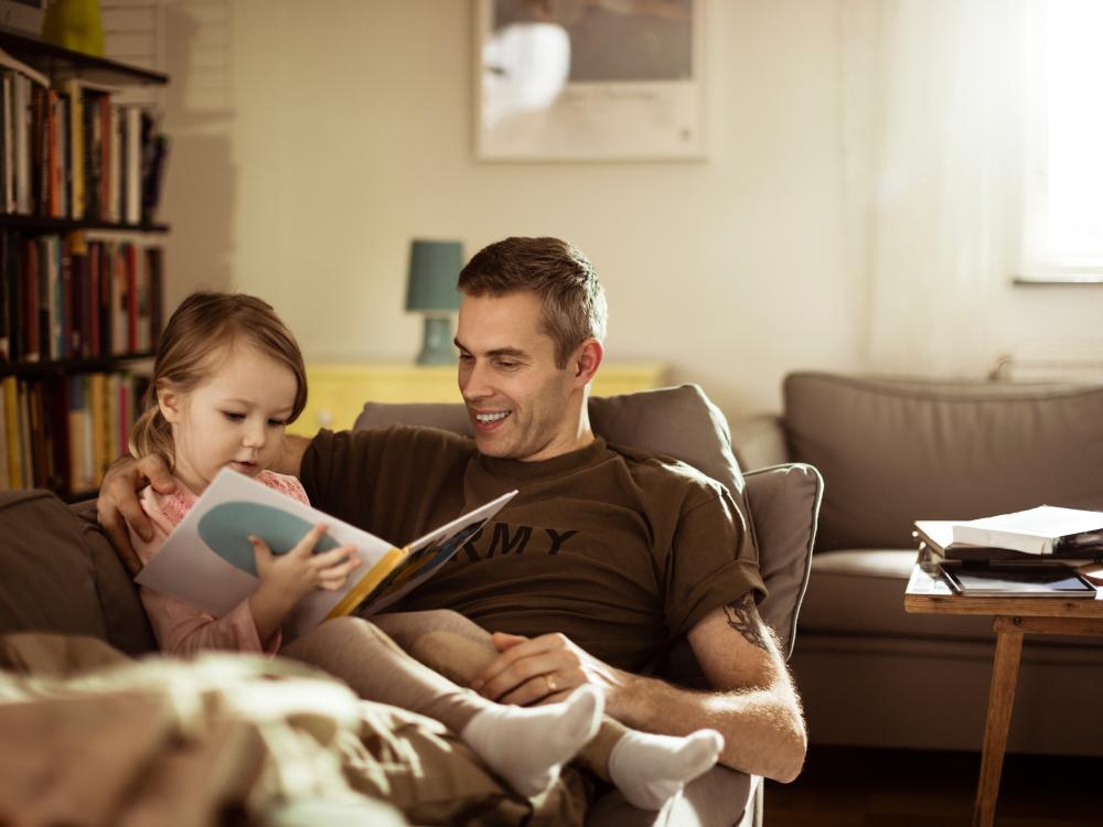 Military father reading book with young daughter.