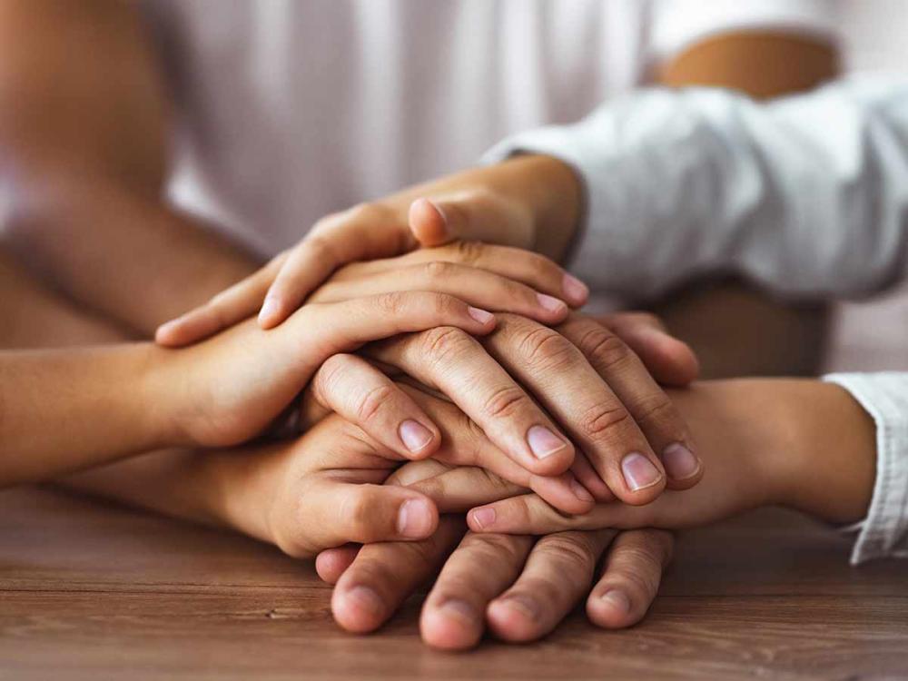 photo of hands of 3 people stacked on top of each other