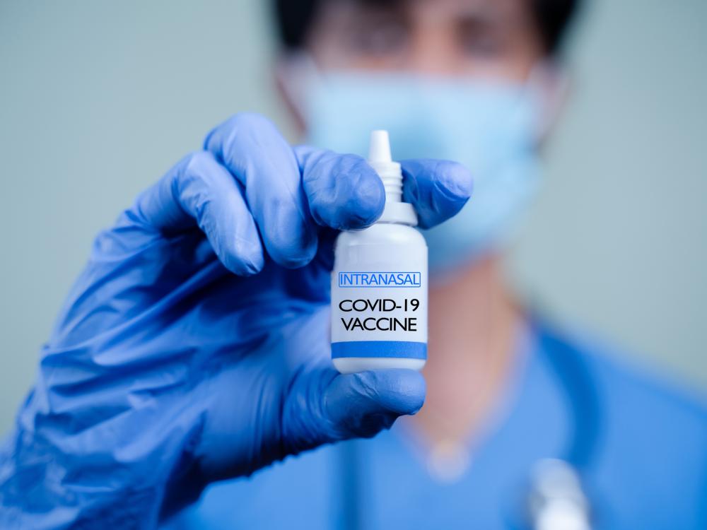 Gloved person holding vial of inhalable COVID-19 vaccine