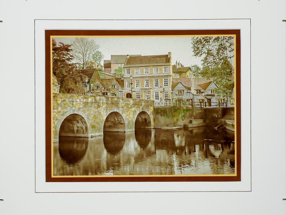 Hand-colored, monochrome photograph of stone bridge and building by Frank Santimauro