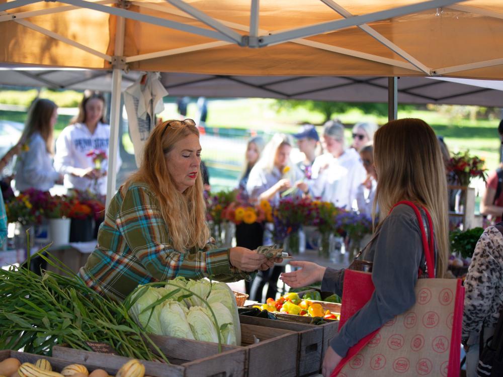 A farmers market vendor makes change for a customer