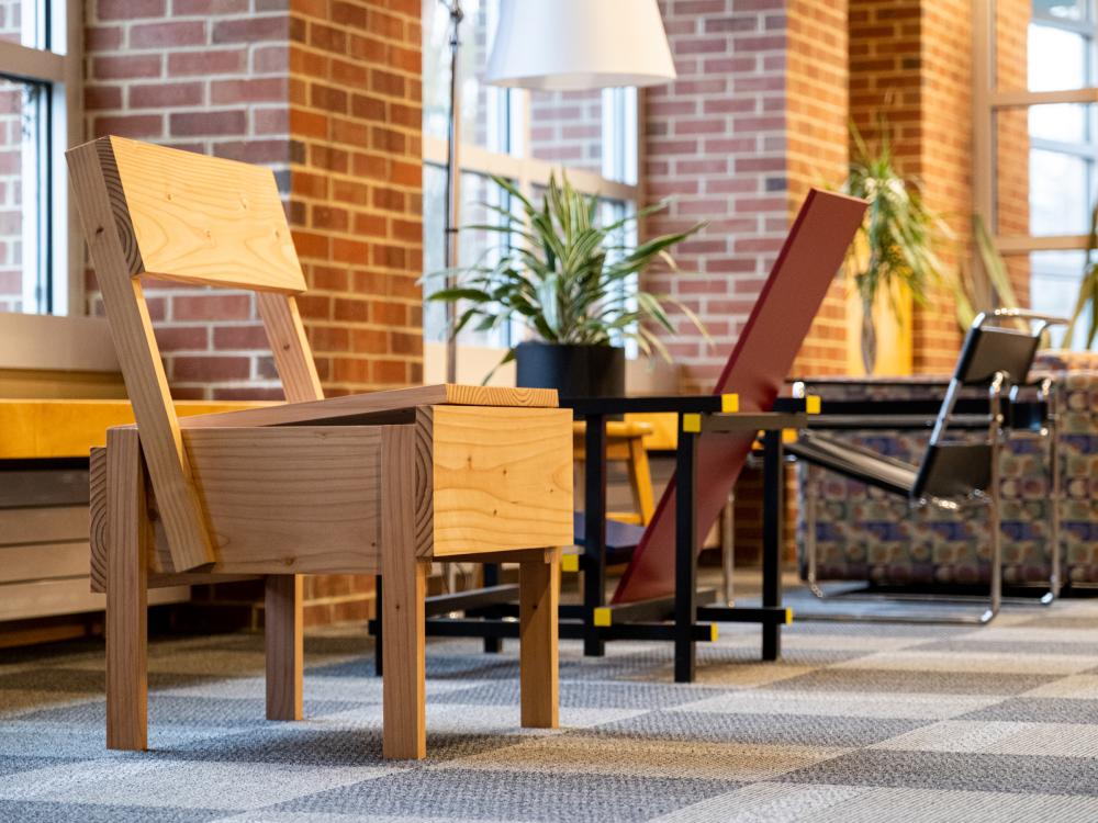 photo of row of three different stylish chairs facing windows in room with wooden chair closest facing interior of room