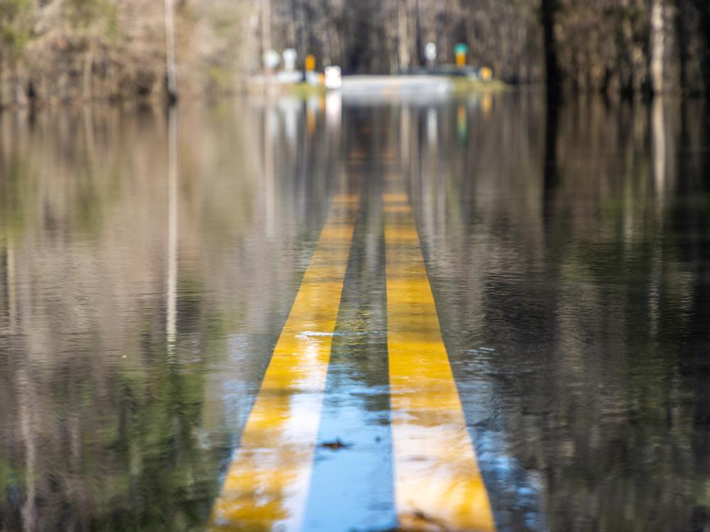 Water floods a paved road. 