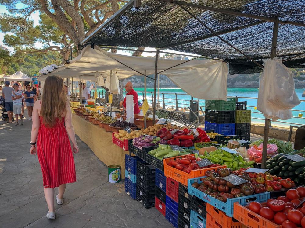 A woman walks past farmers market produce stands