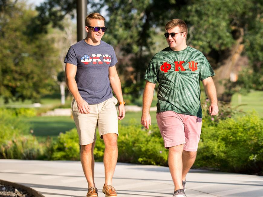 Two students walking wearing Phi Kappa Psi Fraternity shirts