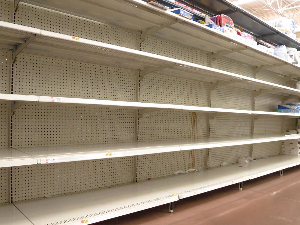 Four empty shelves at a grocery store are shown