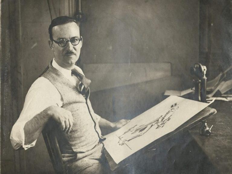 seated man, illustration atop drawing board resting on lap