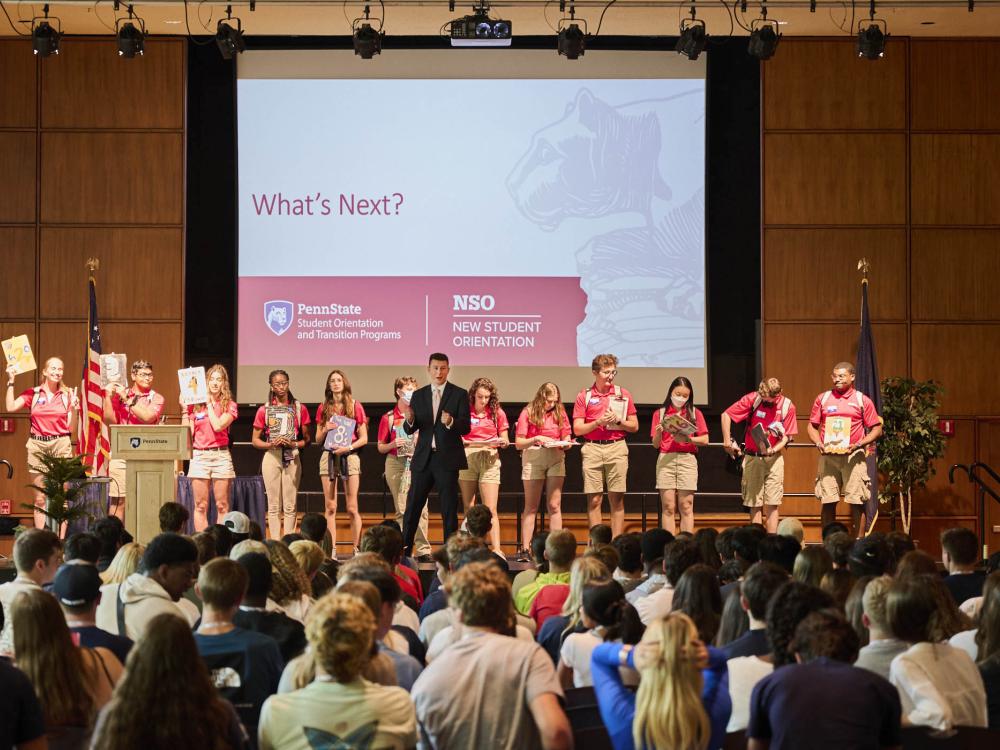 Orientation Leaders and NSO staff presenting on stage in Alumni Hall, with the audience facing away in the foreground